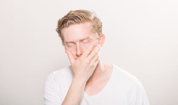 A man with red hair covers his mouth with his hand.