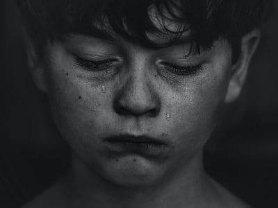 A young boy cries with tears streaming down his face.