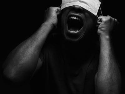 A screaming person has a medical mask covering their eyes.